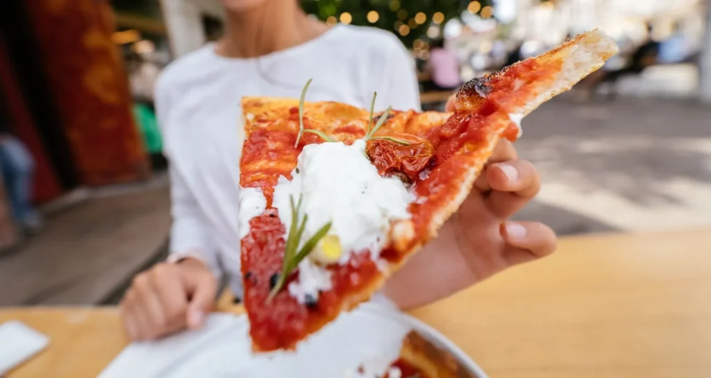Slice of Italian pizza with tomato, creamy cheese and herbs